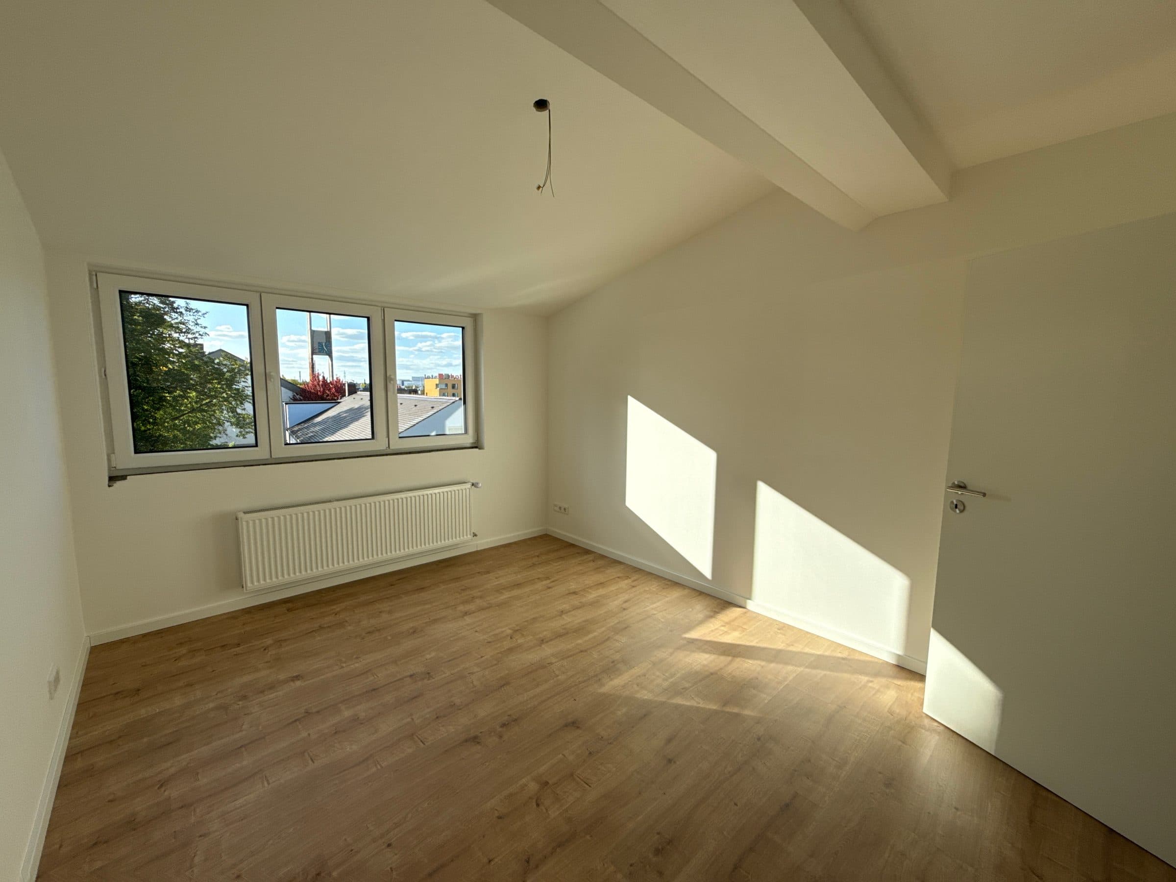 Sonniges Zimmer mit Deckenbalken und Fenster zur Straße