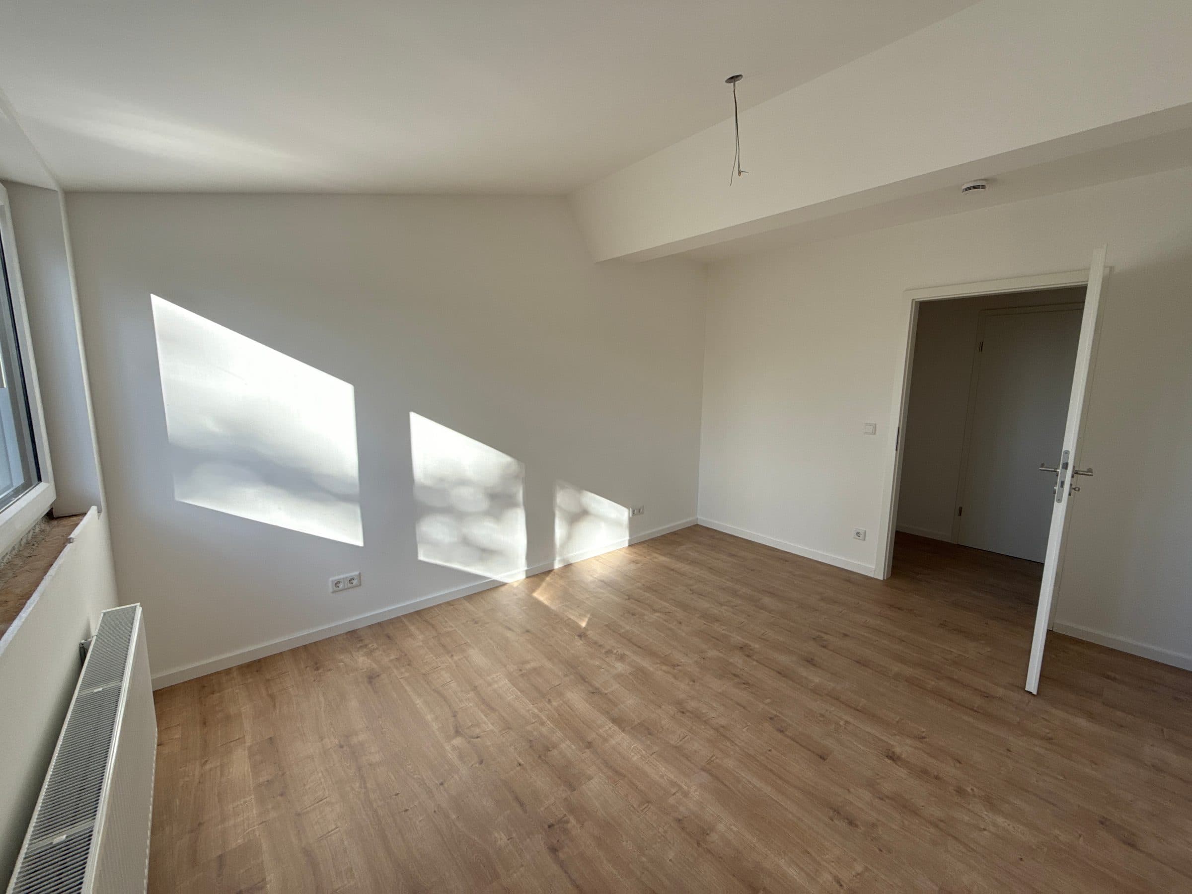Zimmer mit Sonnenlicht auf den Wänden und Holzboden