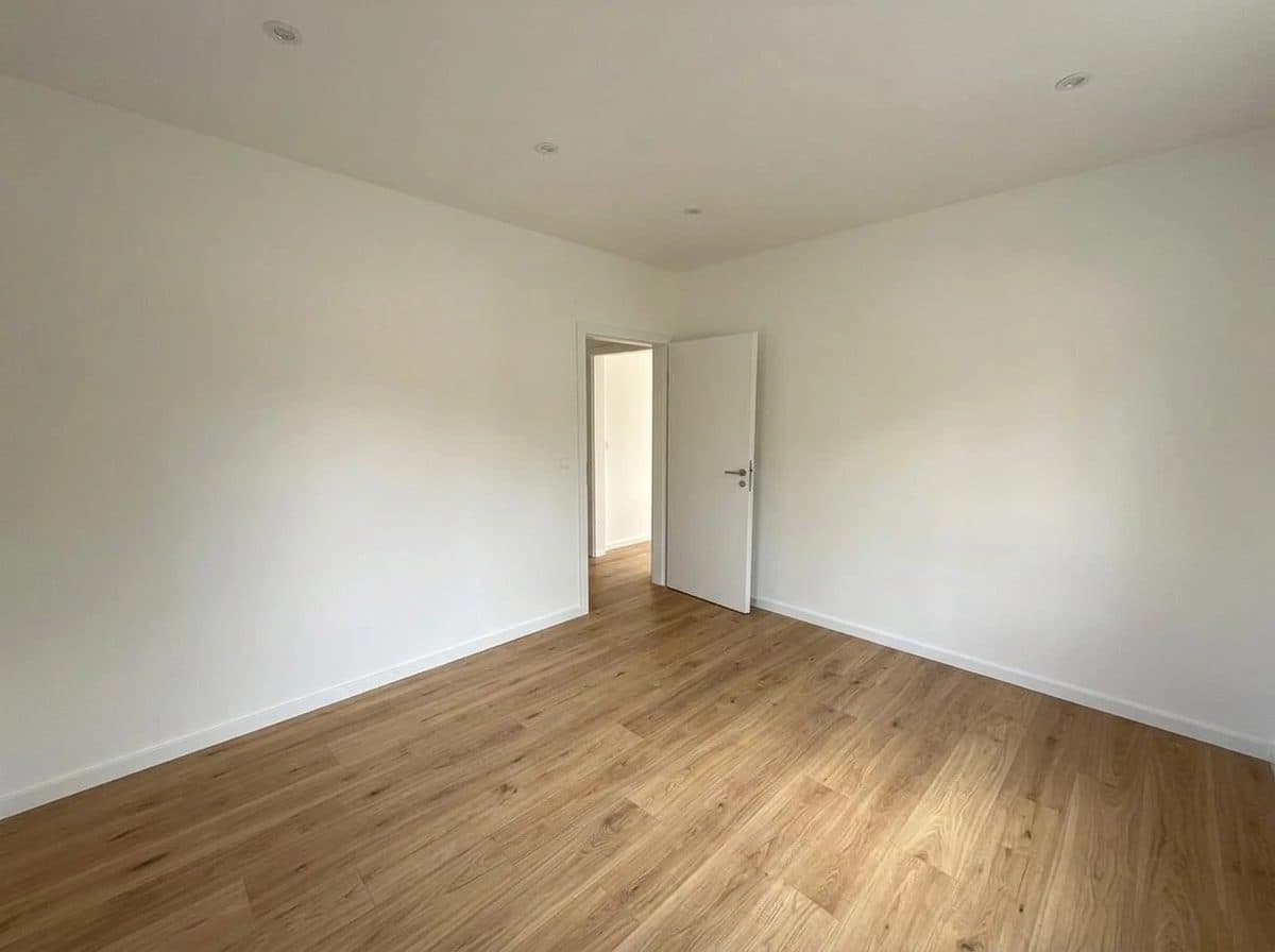 Wohnung 1: Zimmer mit offener Tür und Holzboden