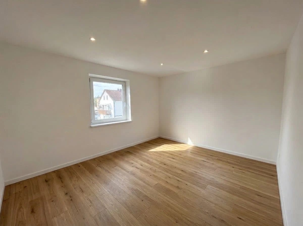 Wohnung 1: Zimmer mit Fenster zur Straße und Holzboden